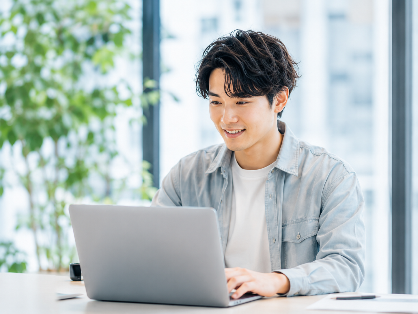 明るいオフィスでノートPCで働く若手エンジニア